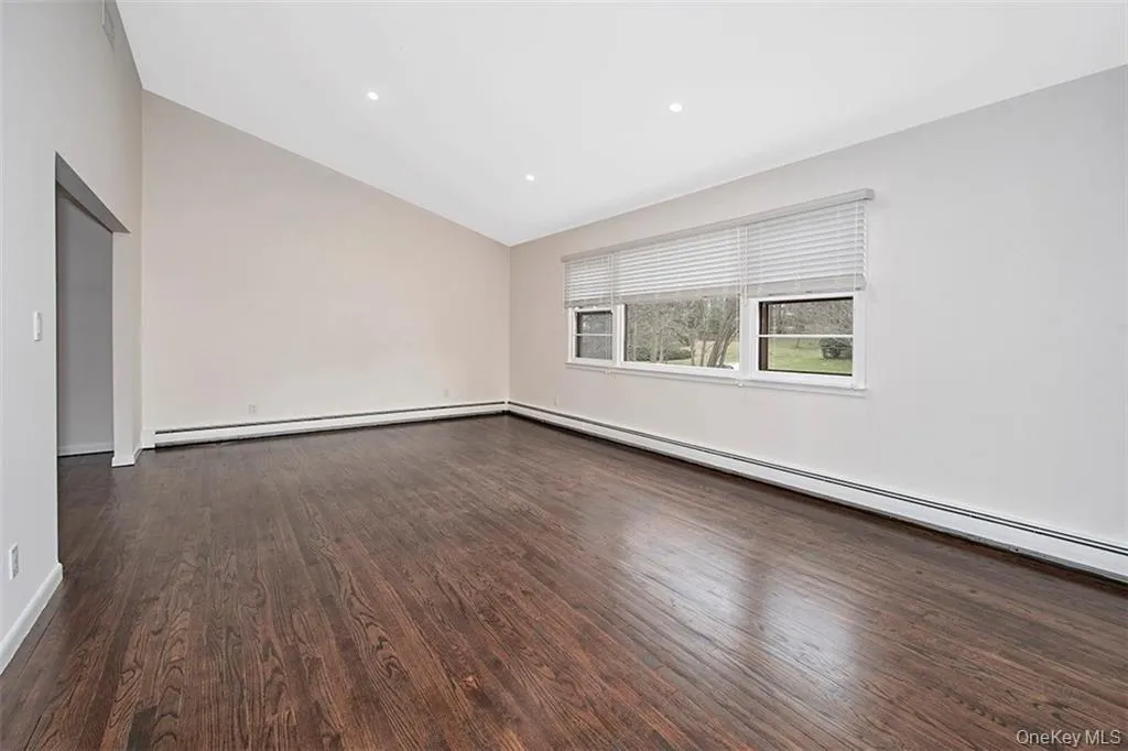 Spacious room featuring rich wood-finish flooring, a vaulted ceiling, recessed lighting, and multiple windows Spacious room featuring rich wood-finish flooring, a vaulted ceiling, recessed lighting, and multiple windows