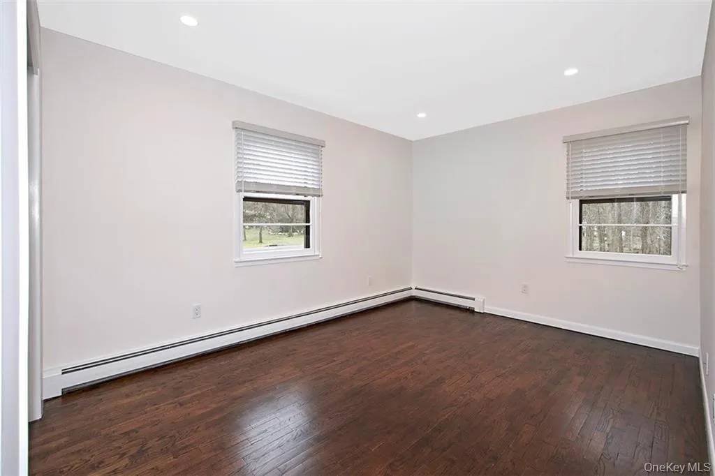 Bedroom featuring dark wood-finish flooring, windows and recessed ceiling lighting Bedroom featuring dark wood-finish flooring, windows and recessed ceiling lighting