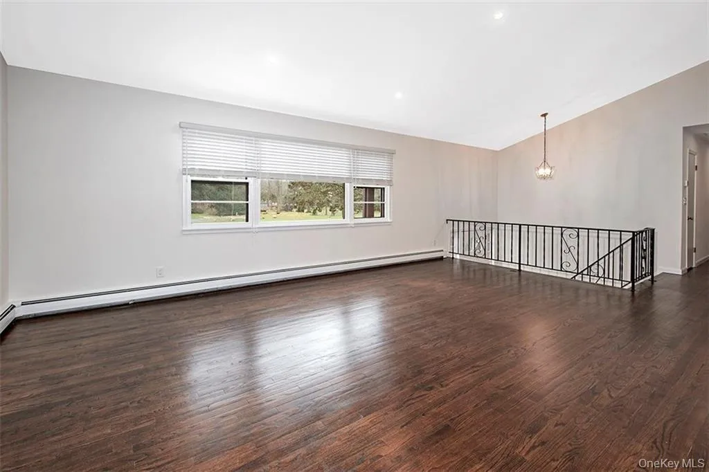 Spacious room featuring rich wood-finish flooring, a vaulted ceiling, recessed lighting, and multiple windows Spacious room featuring rich wood-finish flooring, a vaulted ceiling, recessed lighting, and multiple windows