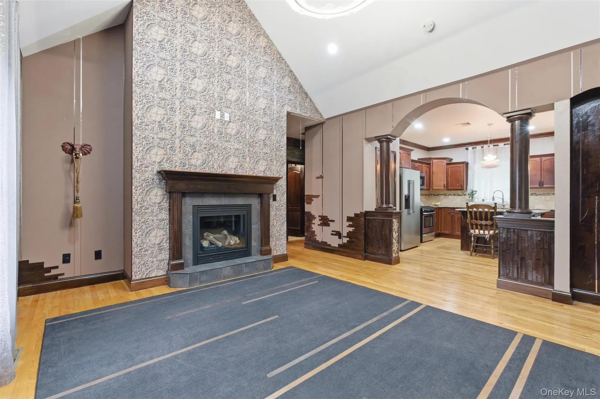 Vaulted ceiling featuring a decorative accent wall and a built-in fireplace with a dark wood mantel Vaulted ceiling featuring a decorative accent wall and a built-in fireplace with a dark wood mantel
