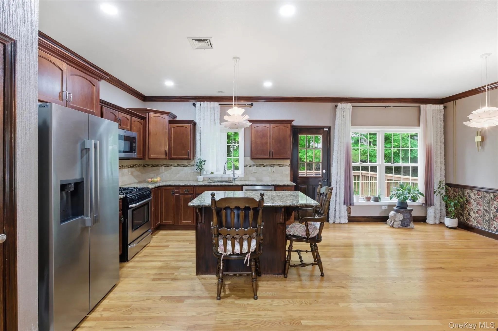 Kitchen featuring a granite-topped island, light wood-finish flooring, recessed lighting, and stainless steel appliances Kitchen featuring a granite-topped island, light wood-finish flooring, recessed lighting, and stainless steel appliances