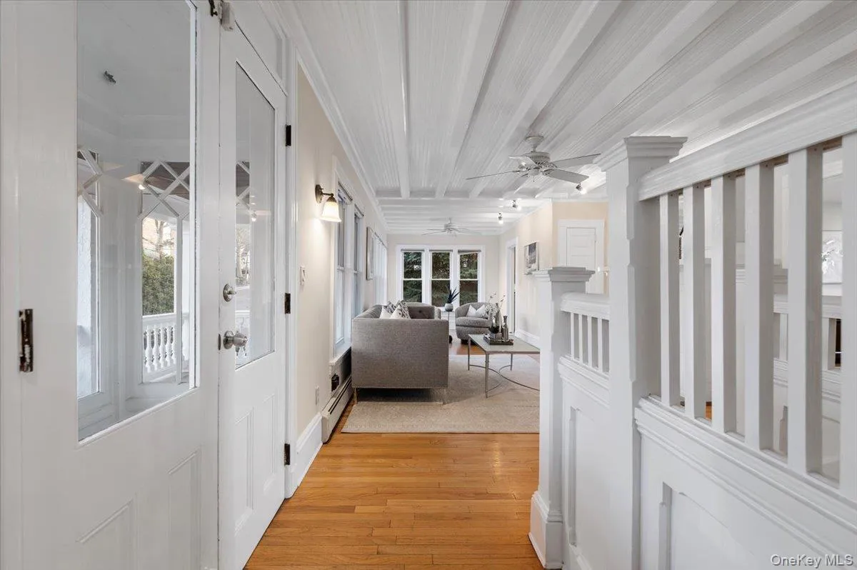 Hallway featuring crown molding, light wood-type flooring, and a baseboard heating unit Hallway featuring crown molding, light wood-type flooring, and a baseboard heating unit