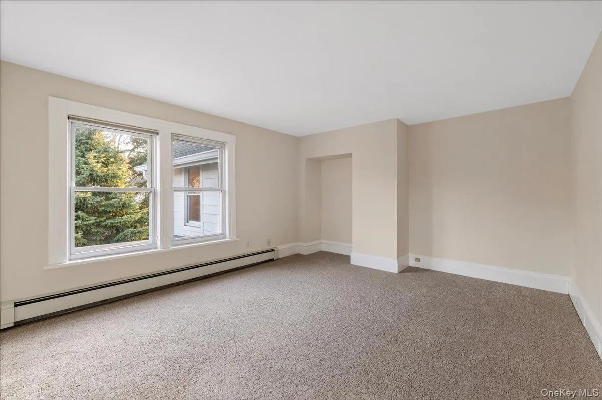 Spare room featuring a baseboard radiator and light colored carpet Spare room featuring a baseboard radiator and light colored carpet
