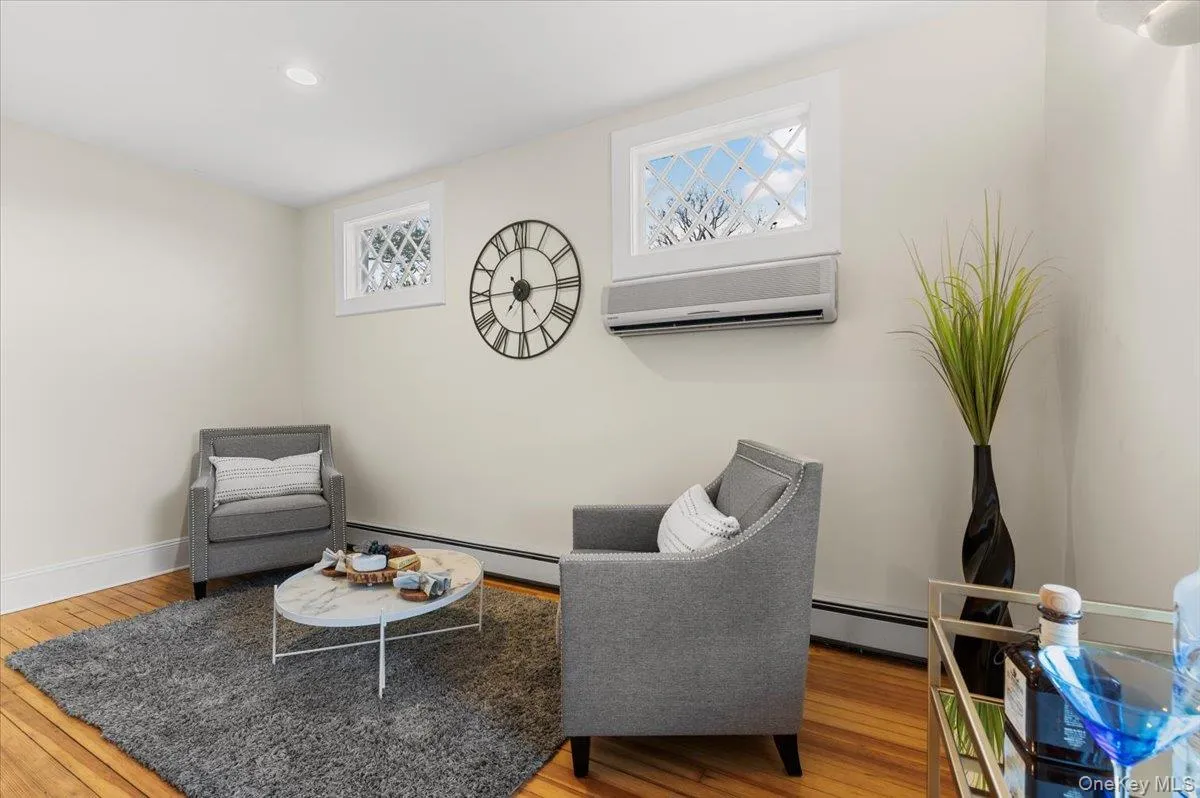 Sitting room with an AC wall unit, light wood finished floors, and a baseboard radiator Sitting room with an AC wall unit, light wood finished floors, and a baseboard radiator