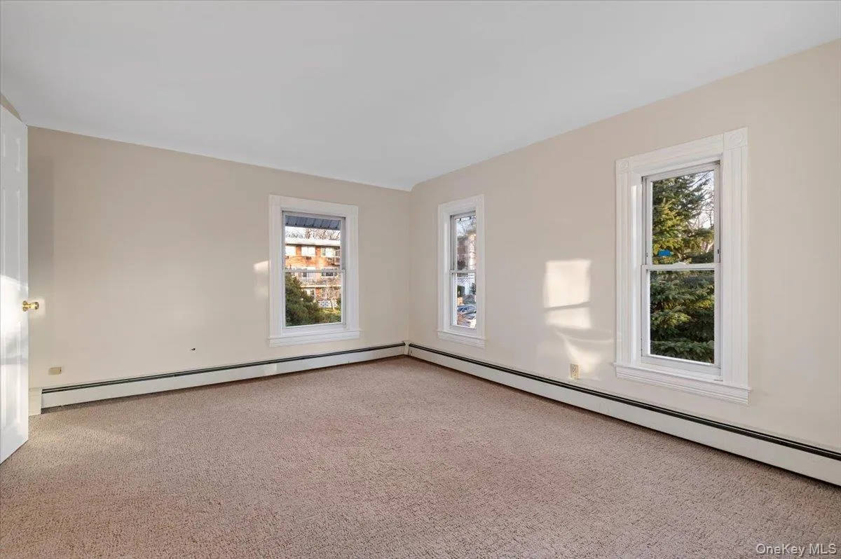 Empty room with carpet floors, a baseboard radiator, and plenty of natural light Empty room with carpet floors, a baseboard radiator, and plenty of natural light