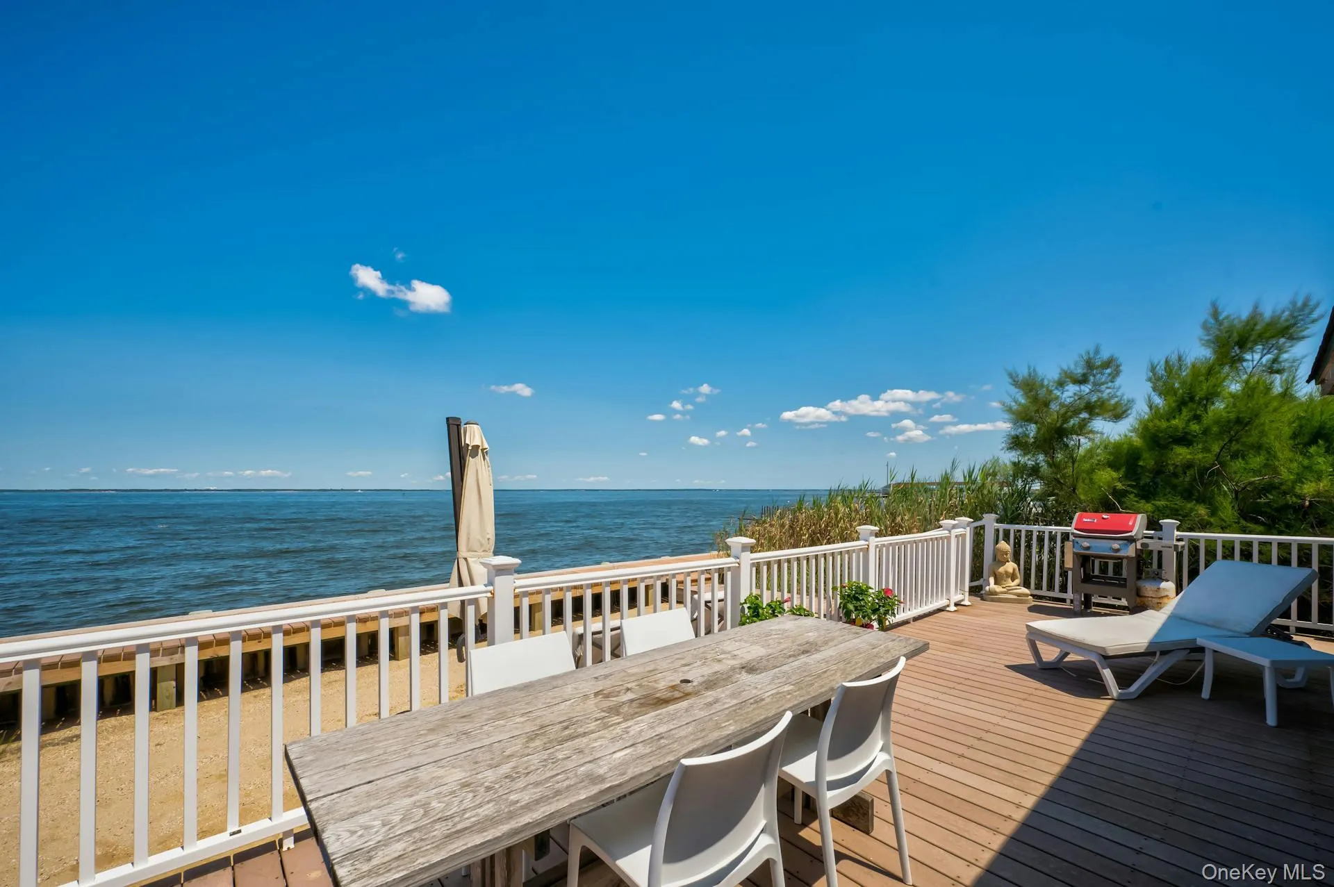 Expansive waterfront deck featuring composite decking and white railing system Expansive waterfront deck featuring composite decking and white railing system