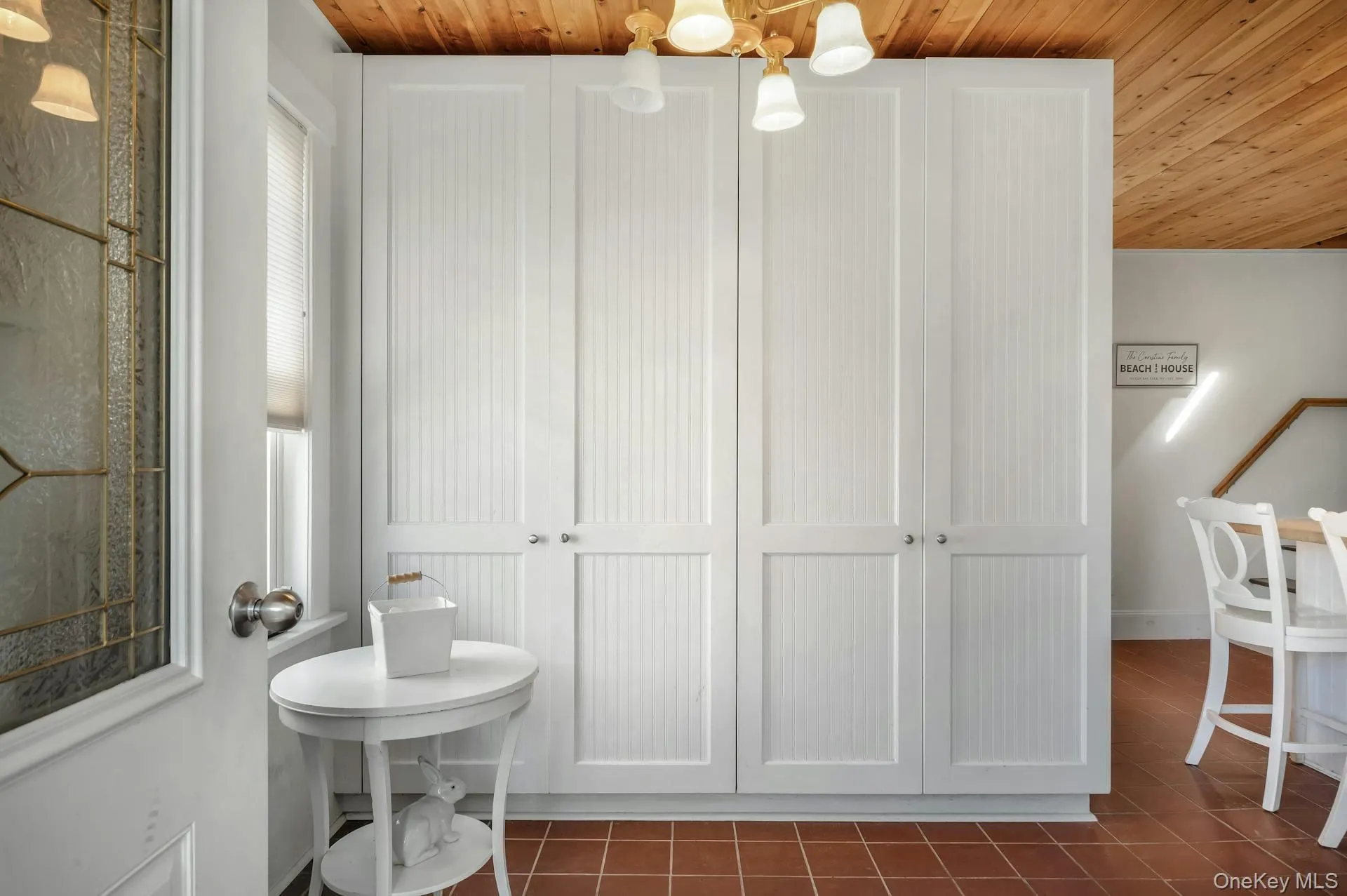 Floor-to-ceiling white beadboard cabinetry with nickel hardware, wood-finish ceiling, and terra cotta tile flooring Floor-to-ceiling white beadboard cabinetry with nickel hardware, wood-finish ceiling, and terra cotta tile flooring