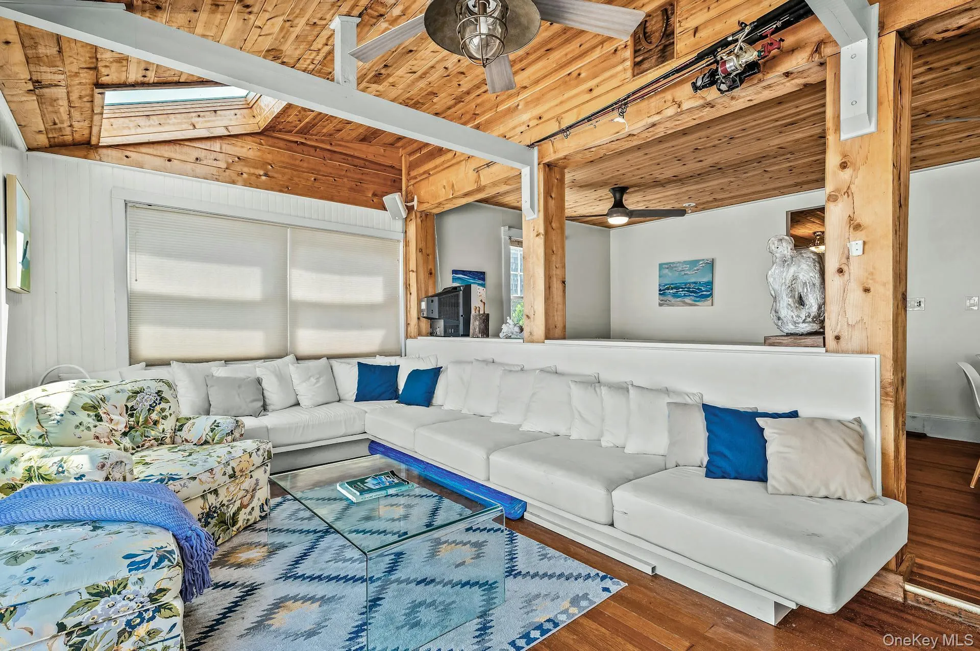 Living area featuring wood-finish flooring, exposed wood beam ceiling, and skylights Living area featuring wood-finish flooring, exposed wood beam ceiling, and skylights