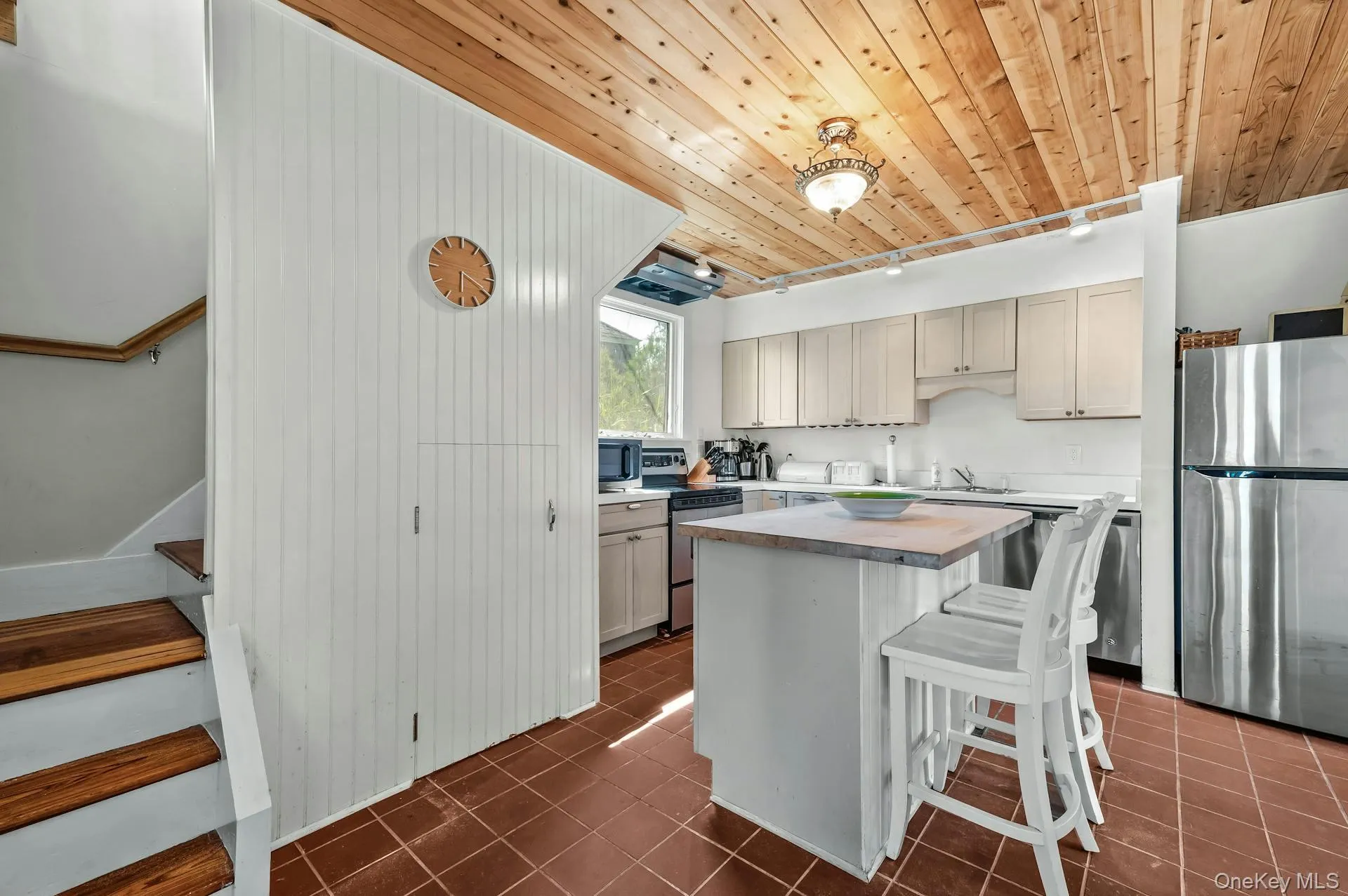 Kitchen with wood-finish ceiling, white cabinetry, and stainless steel appliances Kitchen with wood-finish ceiling, white cabinetry, and stainless steel appliances
