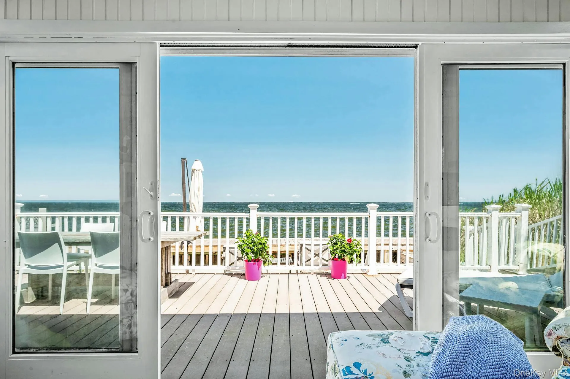 Sliding glass doors opening onto an expansive exterior deck with bay frontage Sliding glass doors opening onto an expansive exterior deck with bay frontage