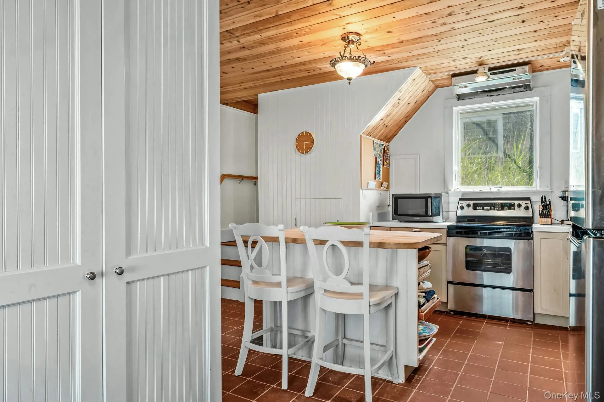 Kitchen featuring a wood-panel ceiling, stainless steel range, and window Kitchen featuring a wood-panel ceiling, stainless steel range, and window