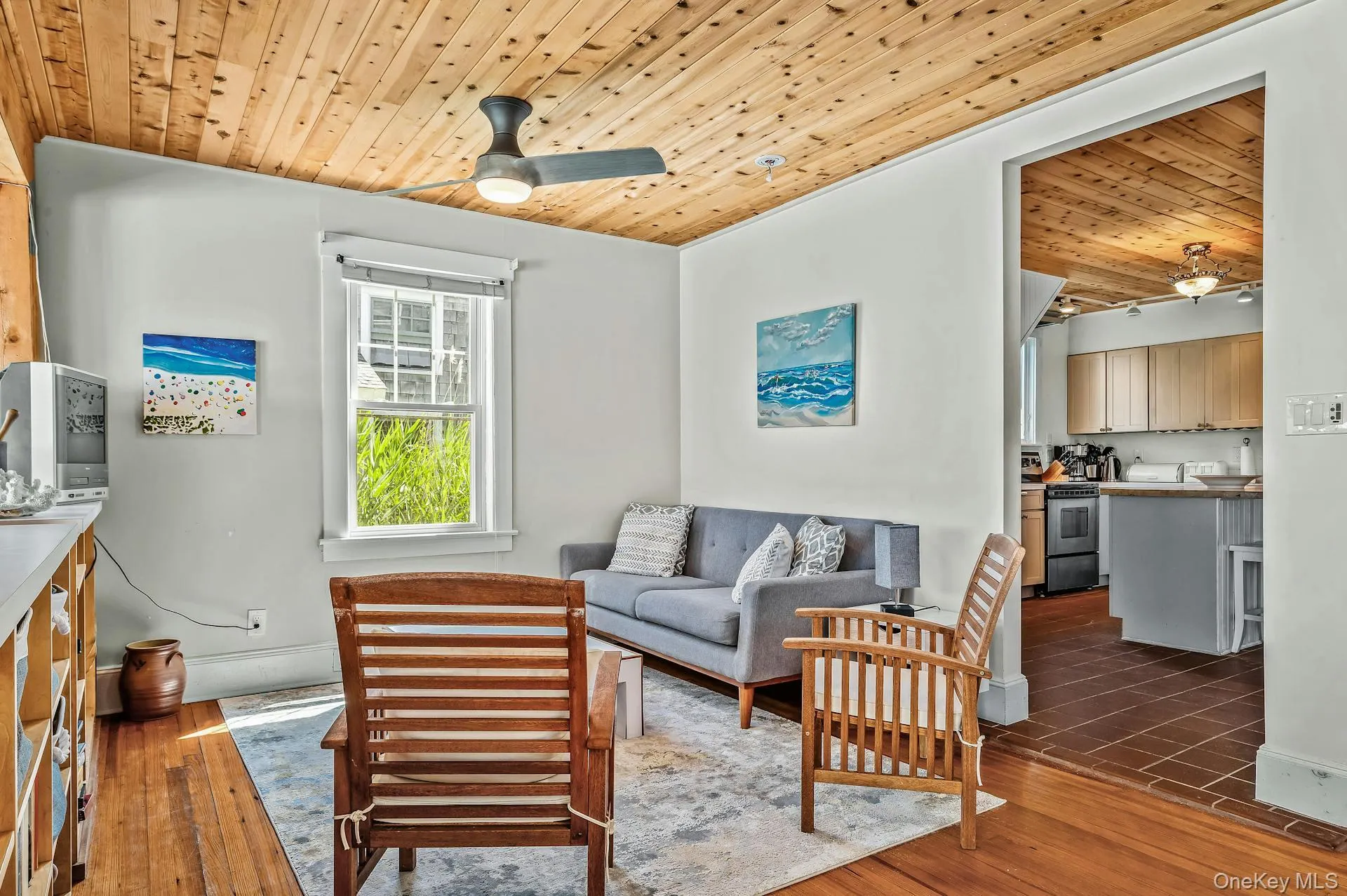 Living area with wood-finish flooring, a wood-paneled ceiling, and a ceiling fan Living area with wood-finish flooring, a wood-paneled ceiling, and a ceiling fan