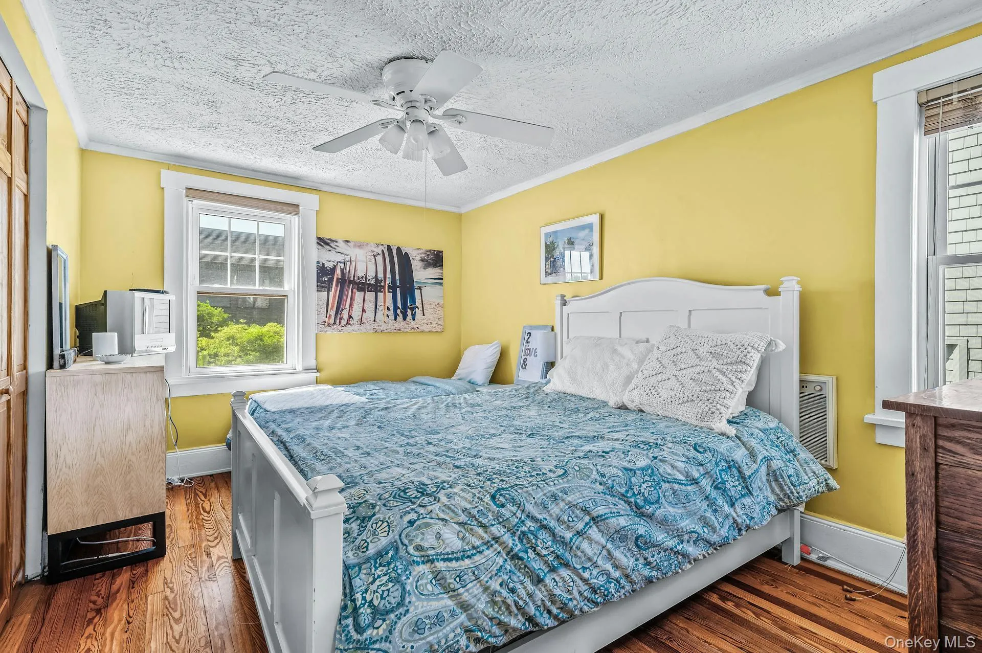 Room featuring wood-finish flooring, a ceiling fan, and multiple windows Room featuring wood-finish flooring, a ceiling fan, and multiple windows