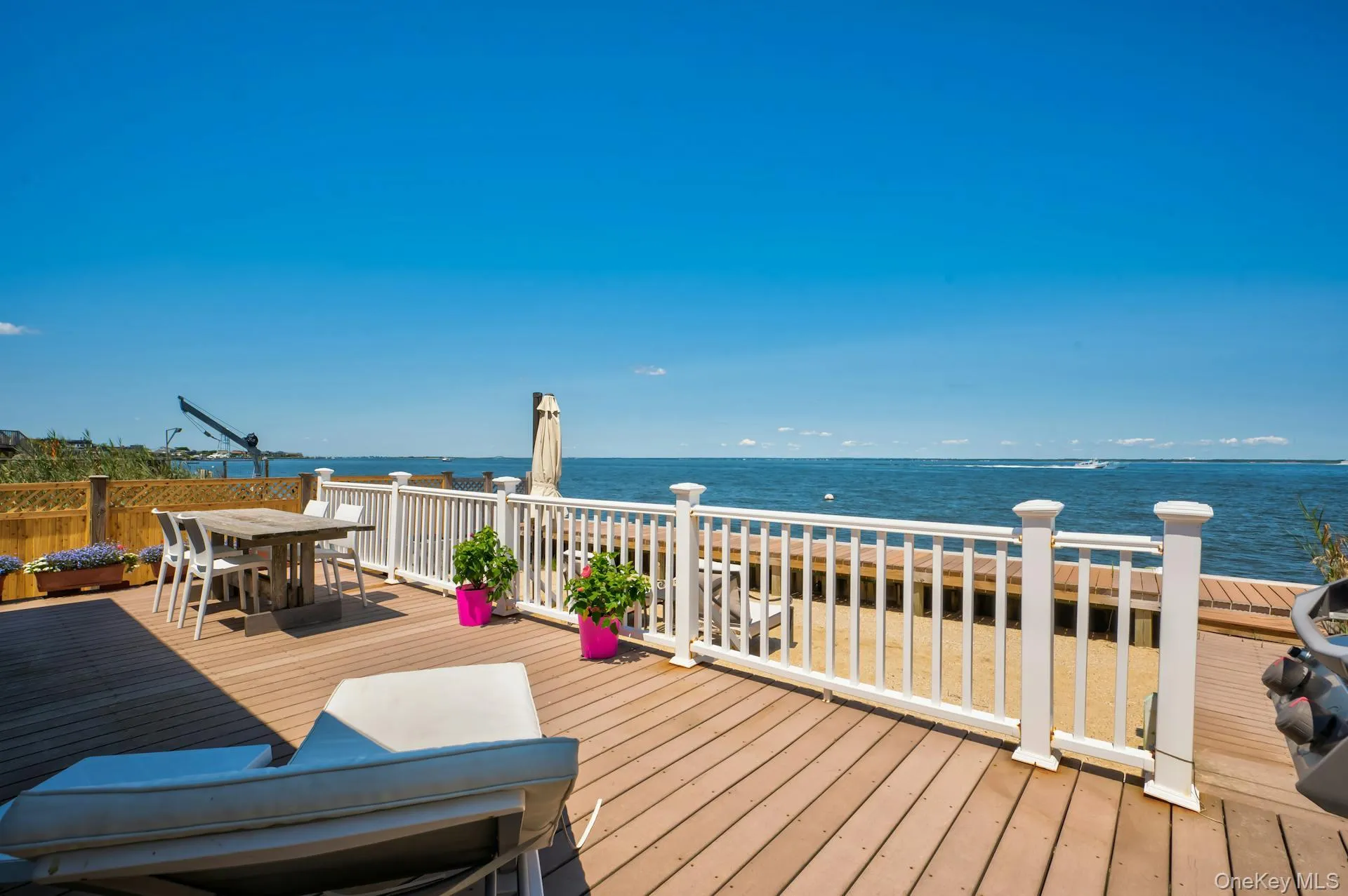 Expansive outdoor deck featuring wood-finish flooring, white railing, and waterfront access Expansive outdoor deck featuring wood-finish flooring, white railing, and waterfront access