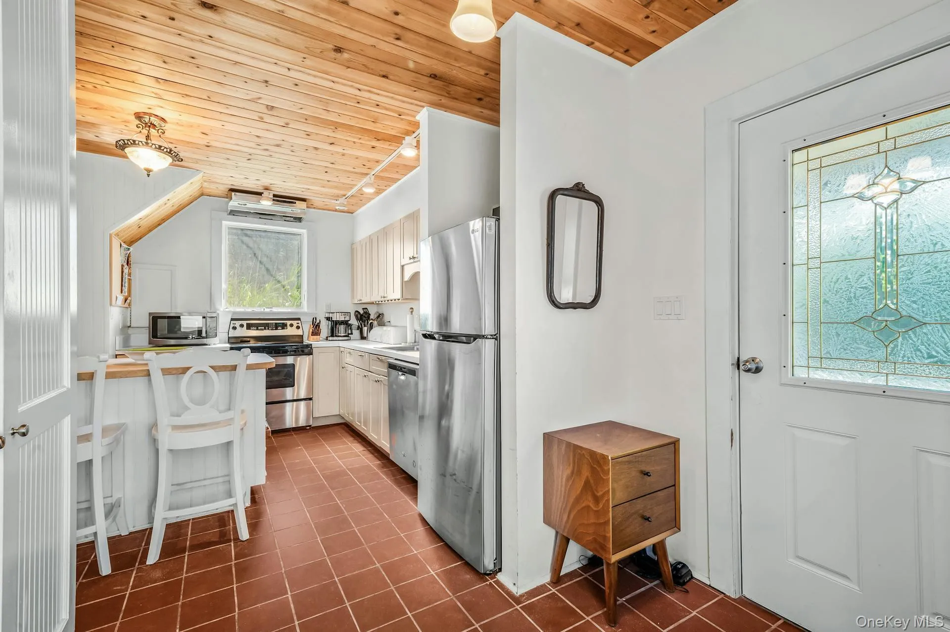 Kitchen featuring a wood-finish ceiling, stainless steel appliances, white cabinetry, and terracotta tile flooring Kitchen featuring a wood-finish ceiling, stainless steel appliances, white cabinetry, and terracotta tile flooring
