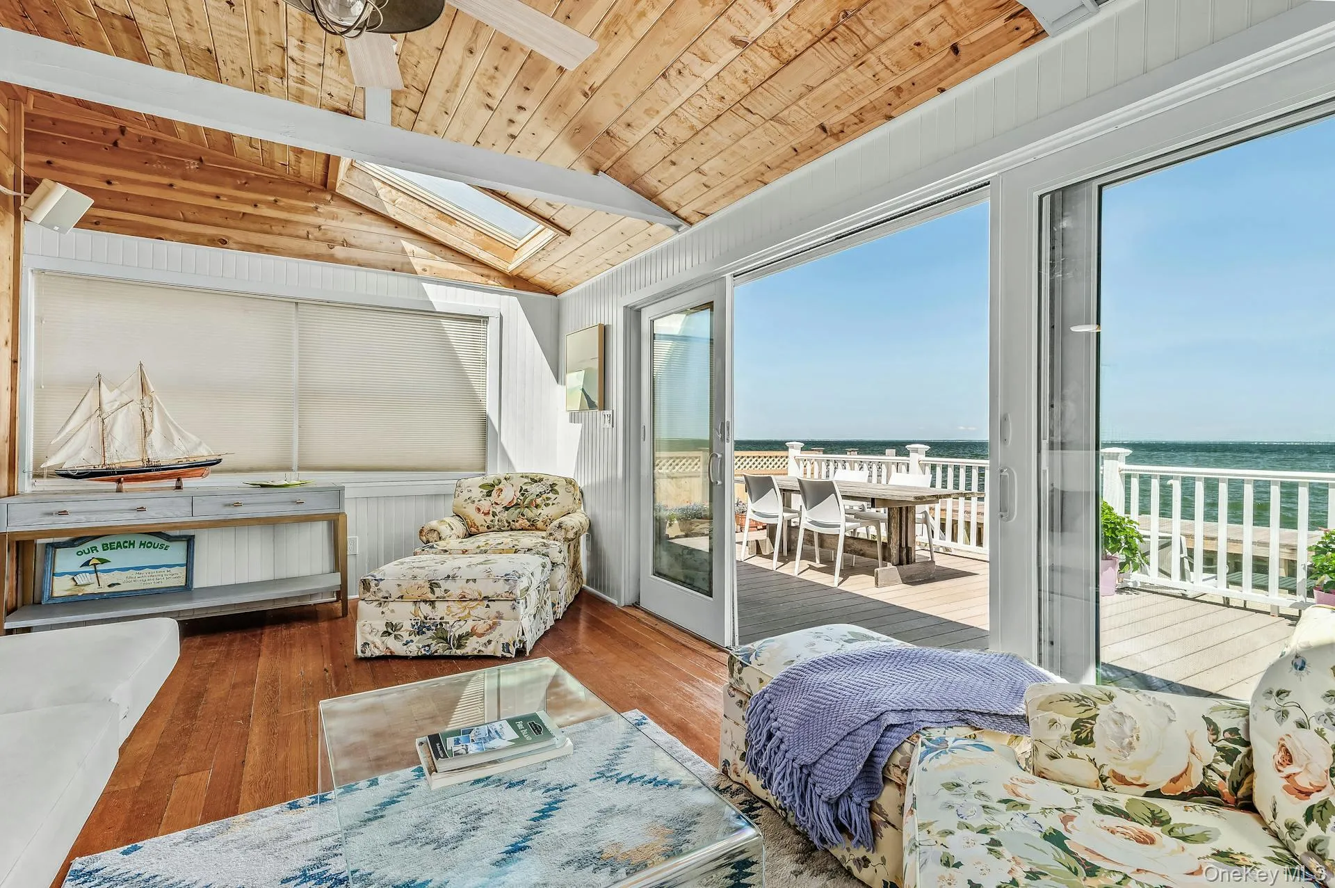 Sunroom featuring wood-finish flooring and a natural wood plank ceiling with exposed beams Sunroom featuring wood-finish flooring and a natural wood plank ceiling with exposed beams