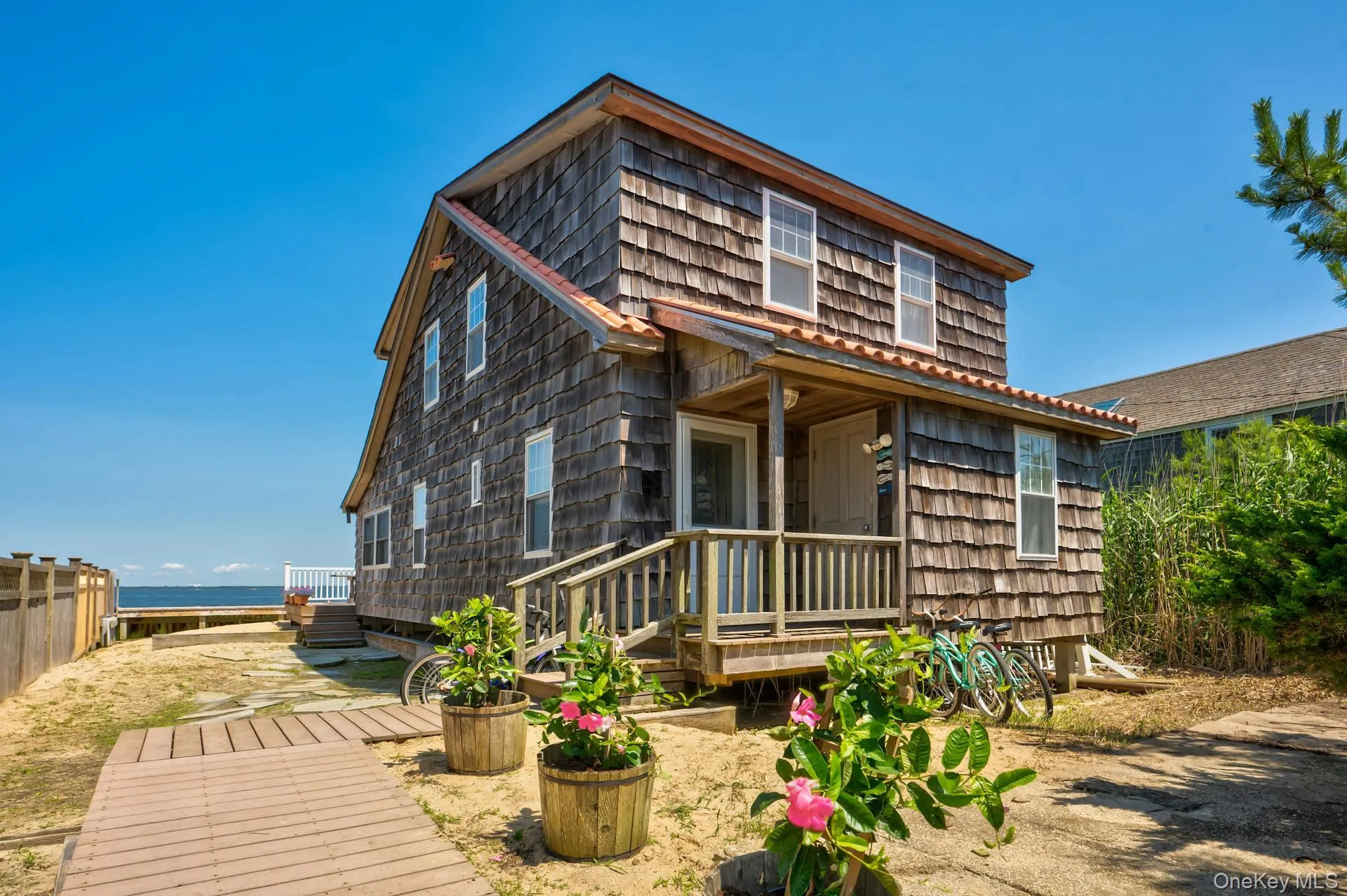 Two-story shingle-sided residence featuring a covered front porch with wood railings Two-story shingle-sided residence featuring a covered front porch with wood railings