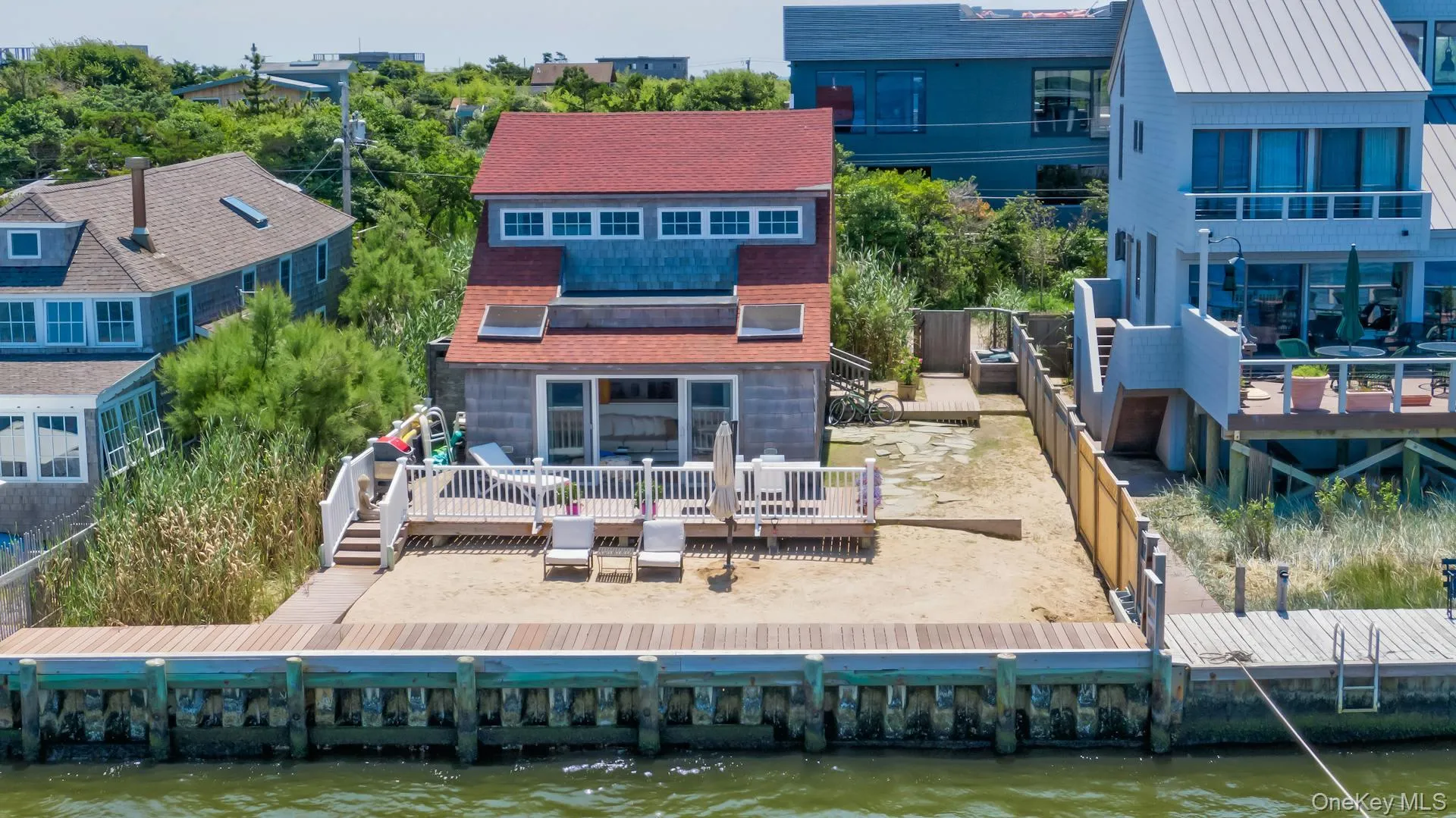Waterfront property featuring a private wood dock and a sand-covered yard Waterfront property featuring a private wood dock and a sand-covered yard