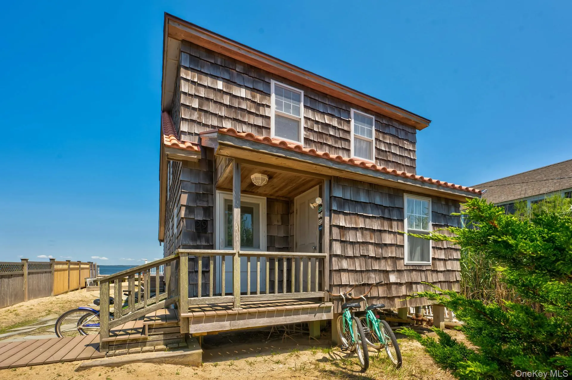 Cedar shake exterior with a covered porch and deck featuring a wooden railing Cedar shake exterior with a covered porch and deck featuring a wooden railing