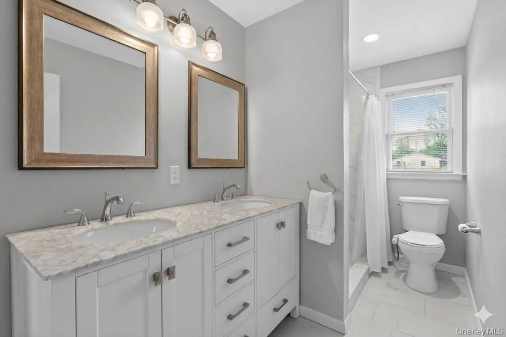 Bathroom featuring a double vanity with stone countertop, dual undermount sinks, and framed mirrors Bathroom featuring a double vanity with stone countertop, dual undermount sinks, and framed mirrors