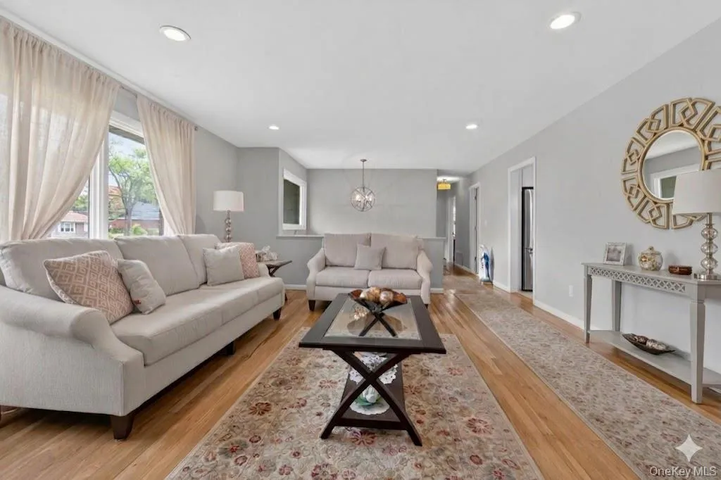 Spacious living area featuring wood-finish flooring, recessed lighting, and large windows Spacious living area featuring wood-finish flooring, recessed lighting, and large windows