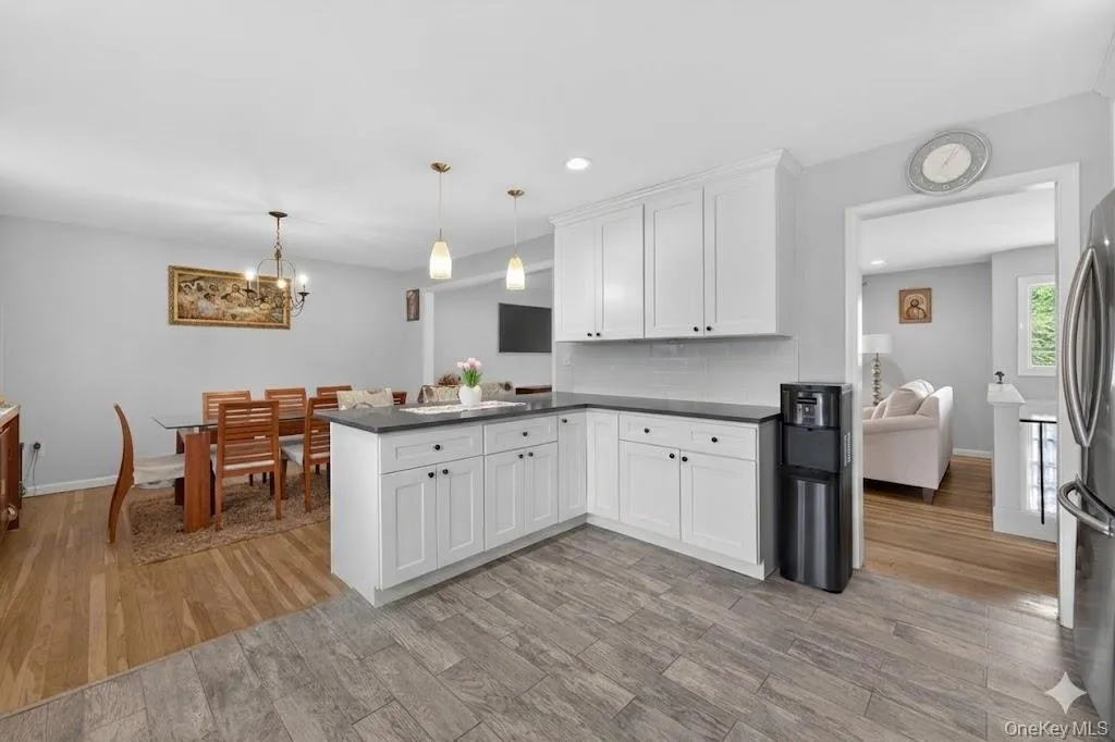 Modern kitchen featuring white shaker cabinetry, dark countertops, and a subway tile backsplash Modern kitchen featuring white shaker cabinetry, dark countertops, and a subway tile backsplash