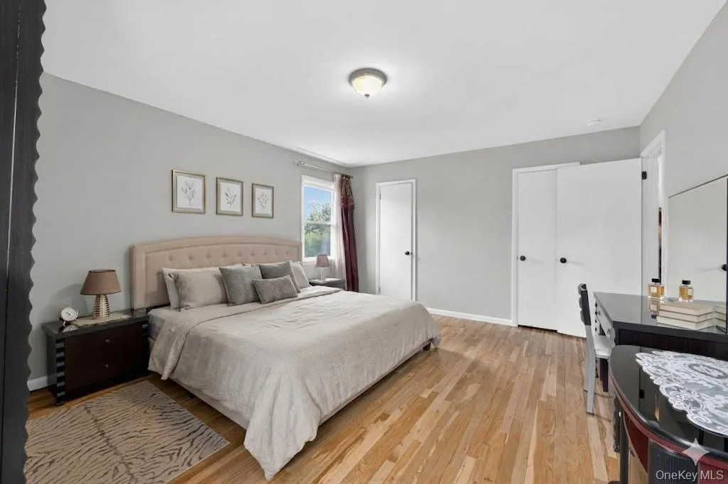 Bedroom featuring wood-finish flooring, light grey walls, and a recessed window with natural light Bedroom featuring wood-finish flooring, light grey walls, and a recessed window with natural light