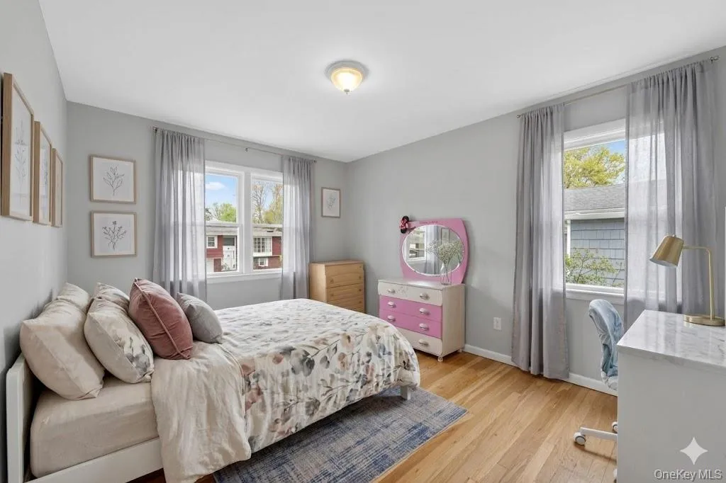 Bright room featuring light wood-finish flooring, light grey walls, and multiple windows Bright room featuring light wood-finish flooring, light grey walls, and multiple windows