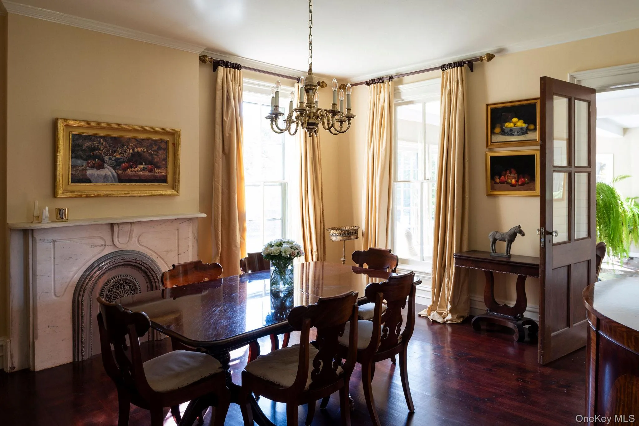 Dining space featuring a chandelier, dark wood-type flooring, healthy amount of natural light, crown molding, and a high end fireplace Dining space featuring a chandelier, dark wood-type flooring, healthy amount of natural light, crown molding, and a high end fireplace