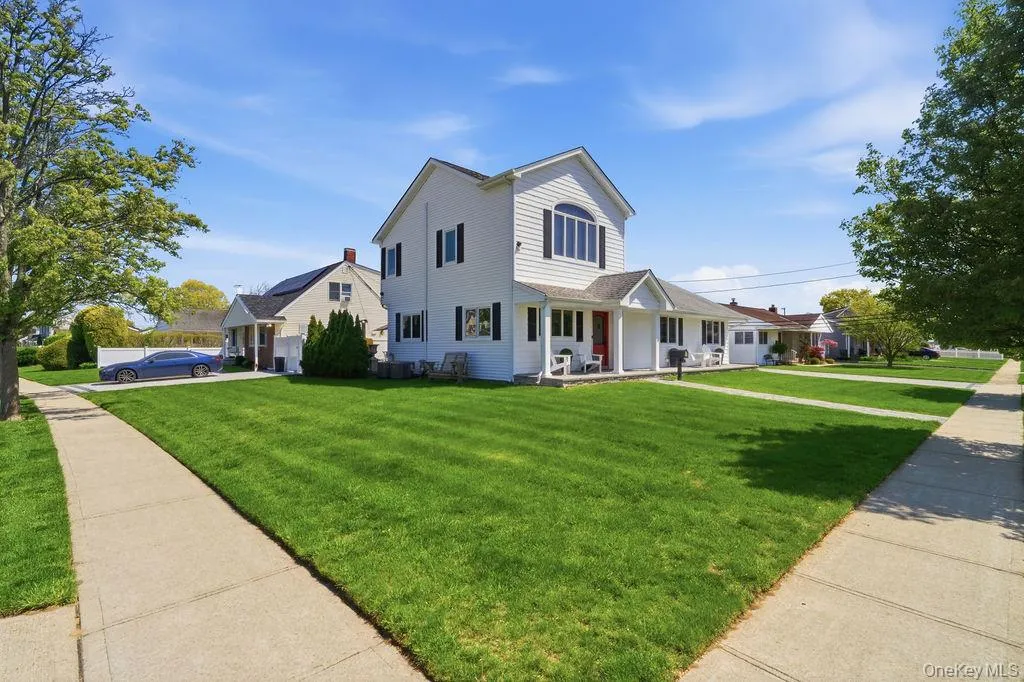 White siding home featuring a prominent arched window, black shutters, and a covered porch with white columns White siding home featuring a prominent arched window, black shutters, and a covered porch with white columns