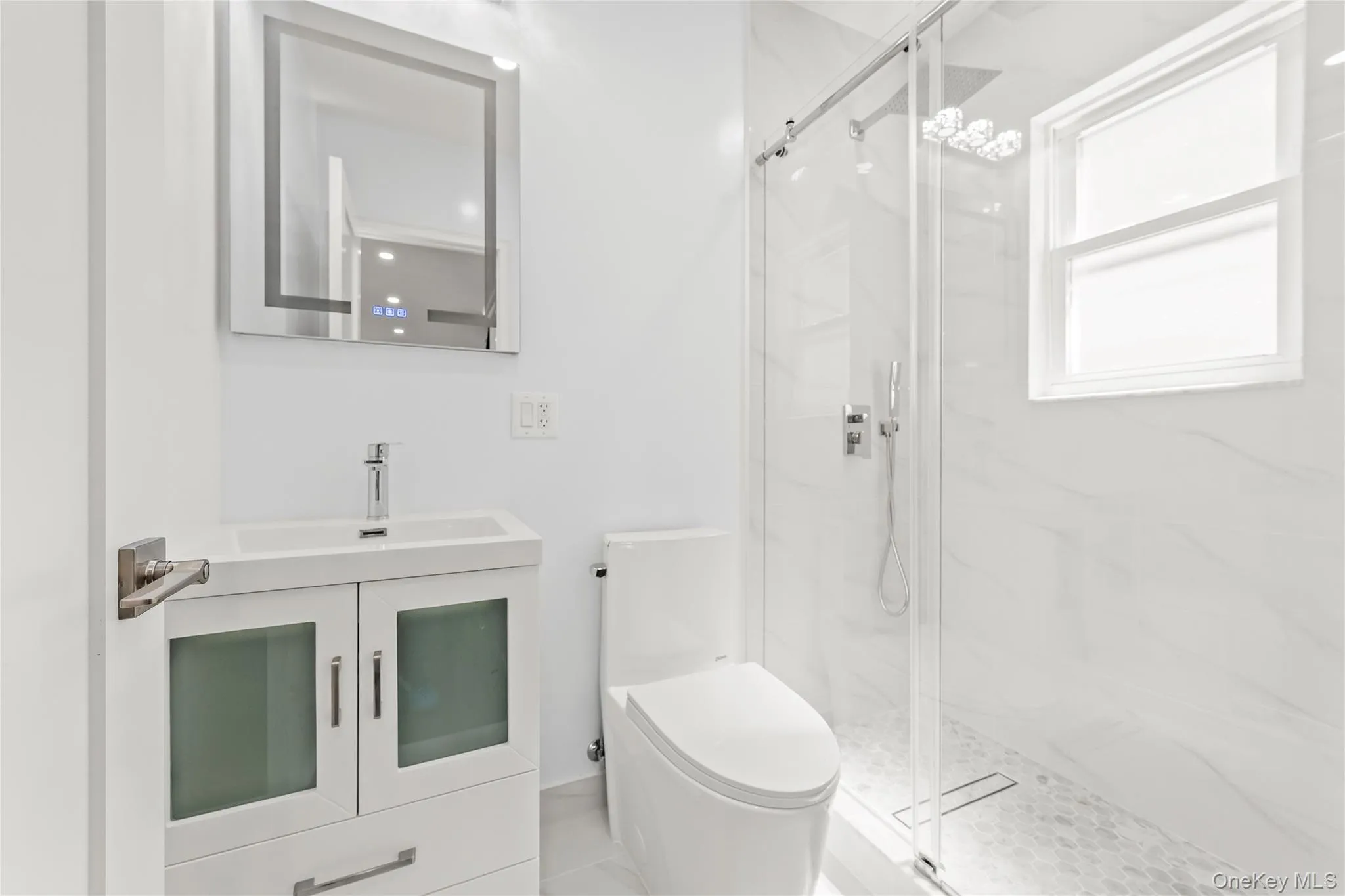 Modern bathroom featuring a glass-enclosed shower with white tiled walls and a pebble-stone floor Modern bathroom featuring a glass-enclosed shower with white tiled walls and a pebble-stone floor