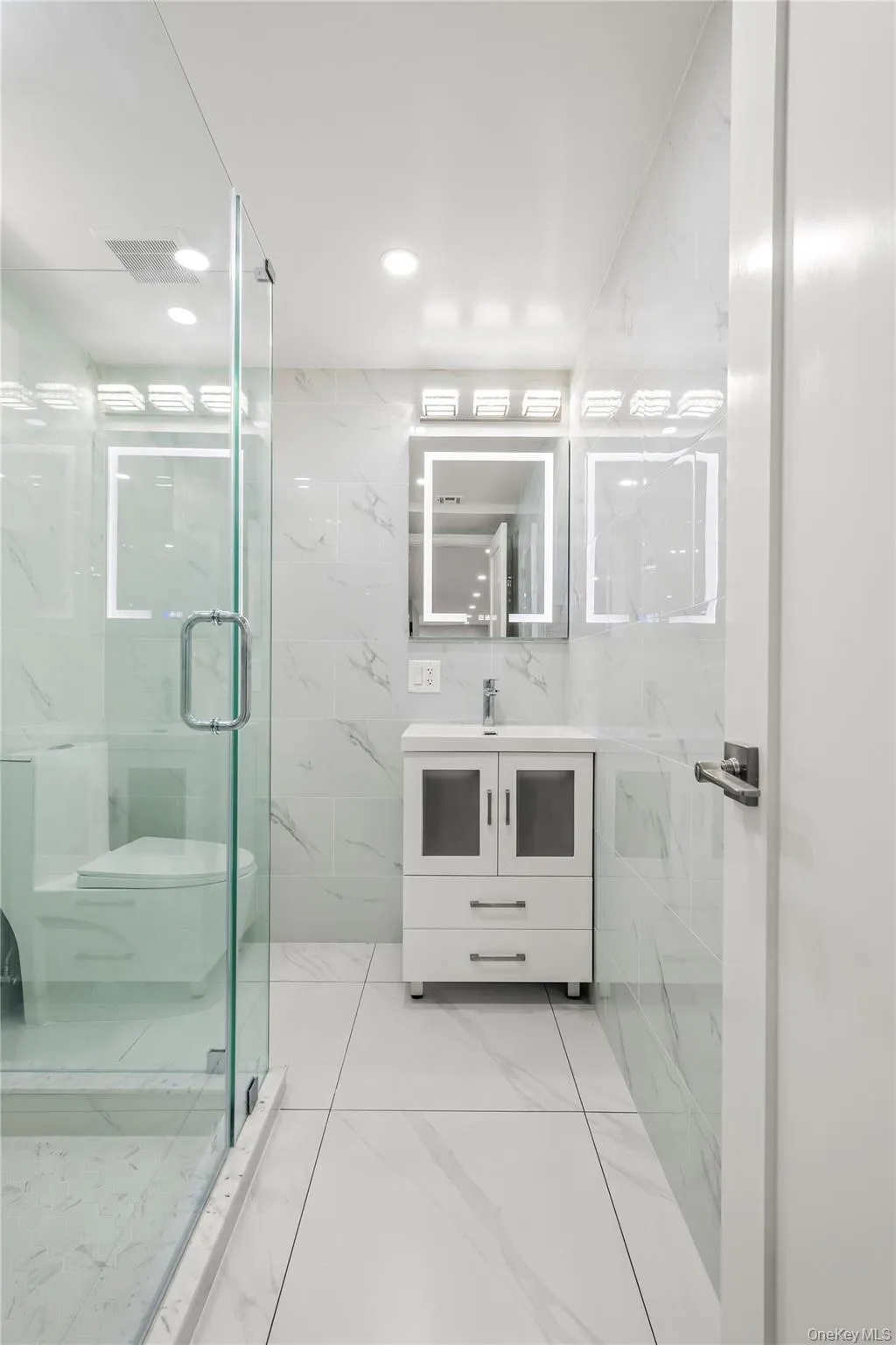 Contemporary bathroom featuring large format tile flooring and wall-to-ceiling tiled walls Contemporary bathroom featuring large format tile flooring and wall-to-ceiling tiled walls