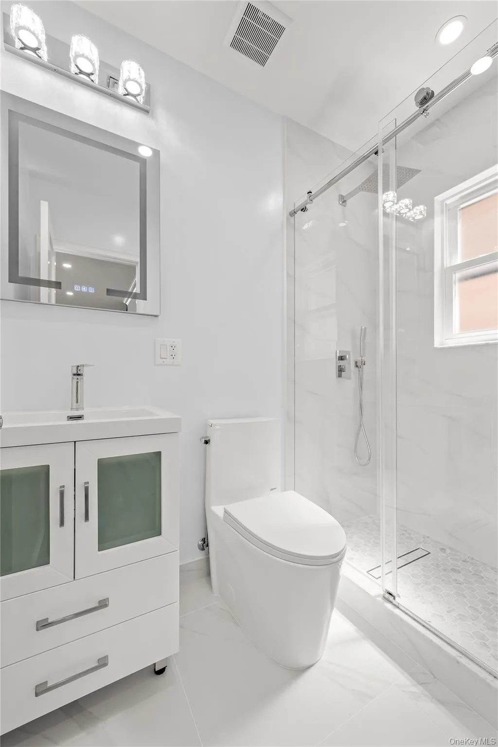 Contemporary bathroom featuring a sleek white vanity with integrated sink, frameless mirror with backlighting, and a modern toilet Contemporary bathroom featuring a sleek white vanity with integrated sink, frameless mirror with backlighting, and a modern toilet