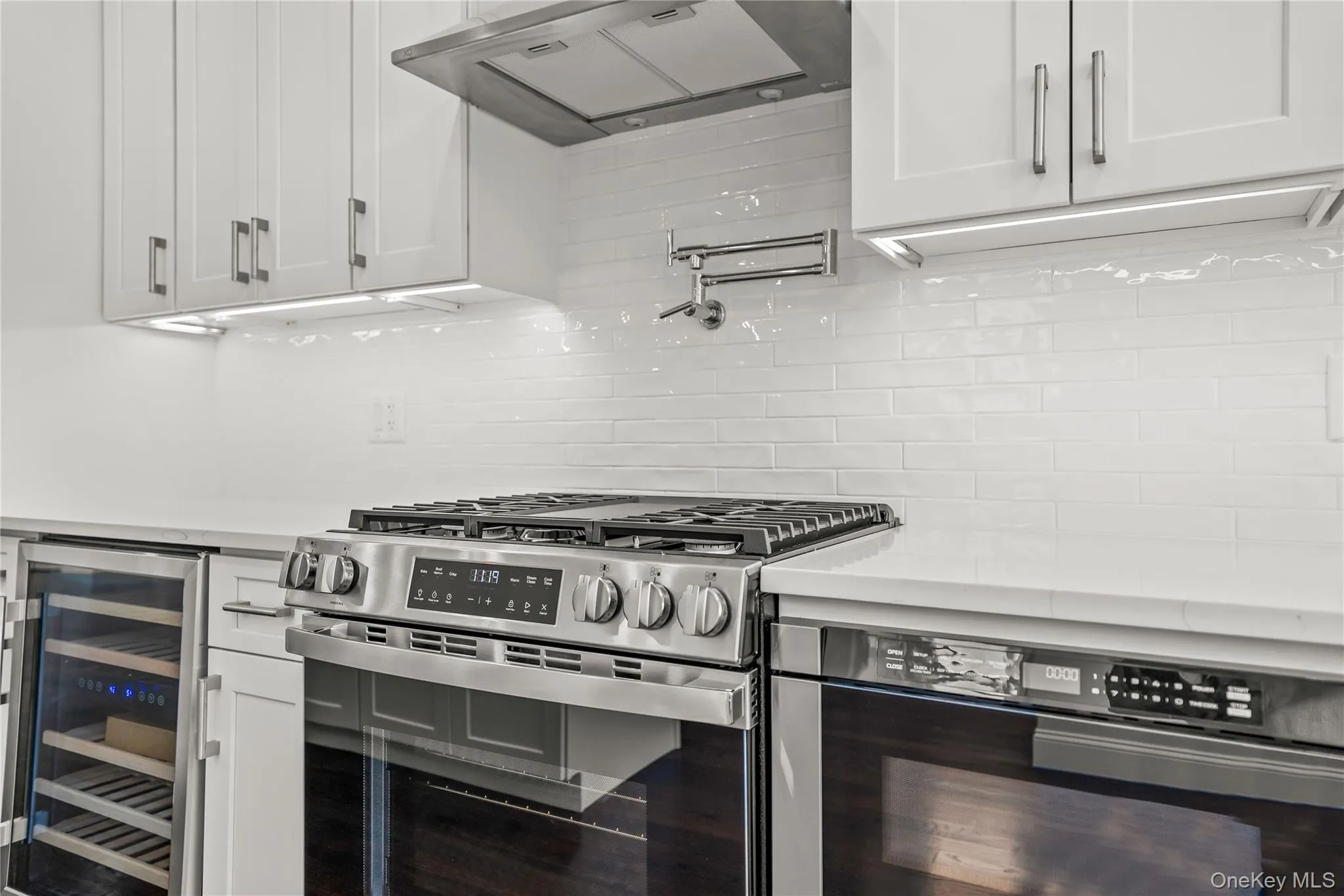 White cabinetry with brushed nickel hardware, under-cabinet lighting, and subway tile backsplash White cabinetry with brushed nickel hardware, under-cabinet lighting, and subway tile backsplash