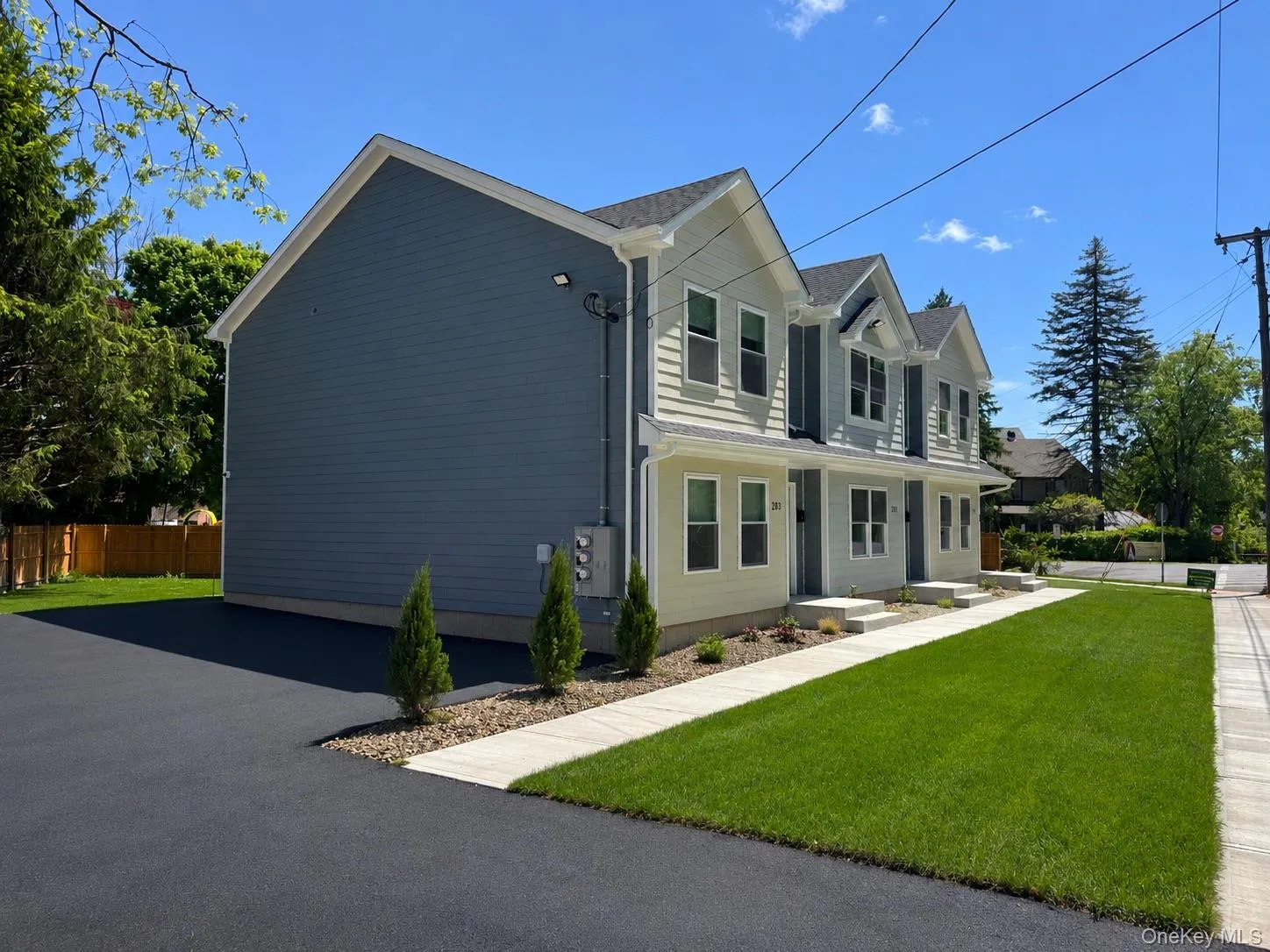 Contemporary duplex featuring a light-toned siding facade with dormer window accents Contemporary duplex featuring a light-toned siding facade with dormer window accents