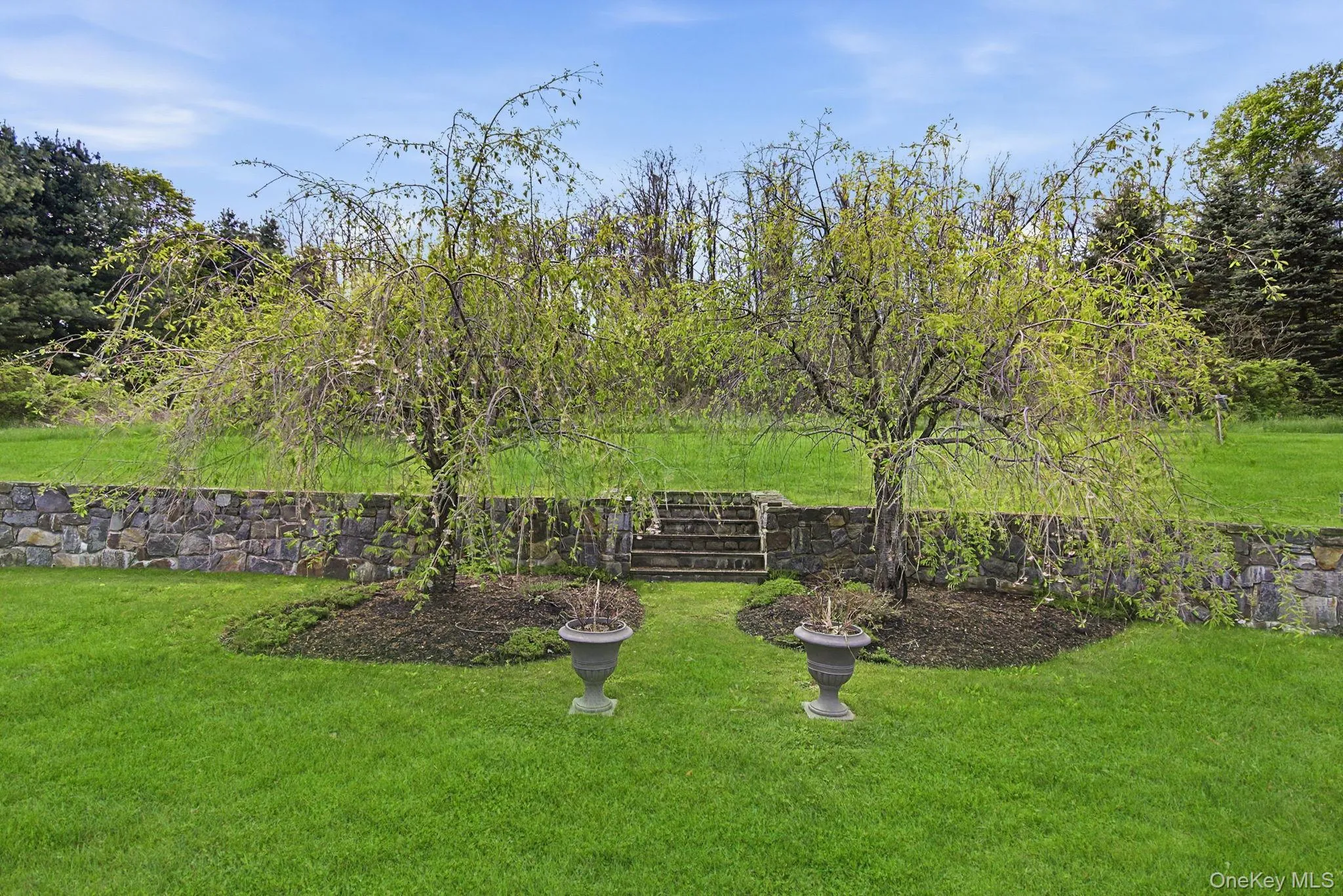 Expansive lawn featuring a natural stone retaining wall, stone steps, and Weeping Cherry Trees Expansive lawn featuring a natural stone retaining wall, stone steps, and Weeping Cherry Trees