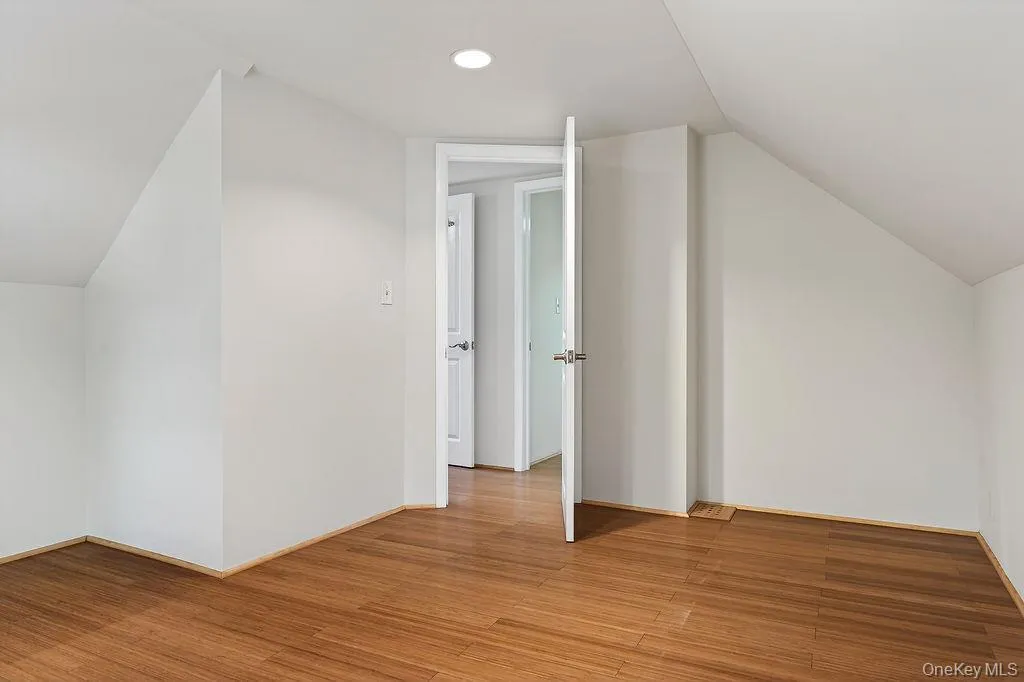 Spacious room featuring wood-finish flooring, white walls, and recessed ceiling lighting. Spacious room featuring wood-finish flooring, white walls, and recessed ceiling lighting.
