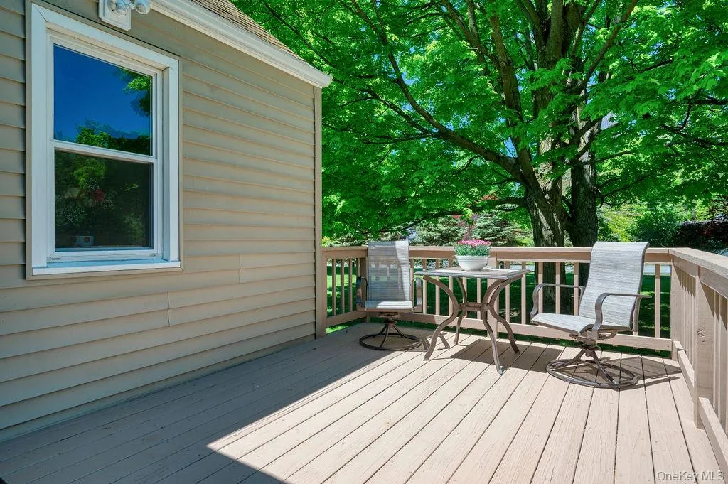 Expansive deck featuring wood-finish flooring and sturdy railings, accompanied by a mature tree Expansive deck featuring wood-finish flooring and sturdy railings, accompanied by a mature tree