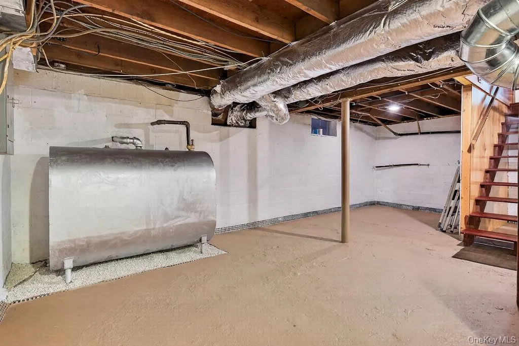Unfinished basement featuring a utility tank and a wooden staircase. Unfinished basement featuring a utility tank and a wooden staircase.