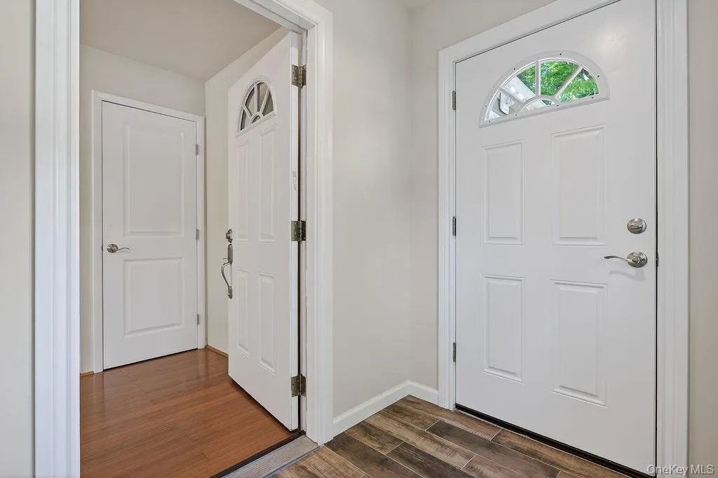 Entryway featuring a paneled door with an arched transom window, chrome hardware, and wood-look tile flooring Entryway featuring a paneled door with an arched transom window, chrome hardware, and wood-look tile flooring