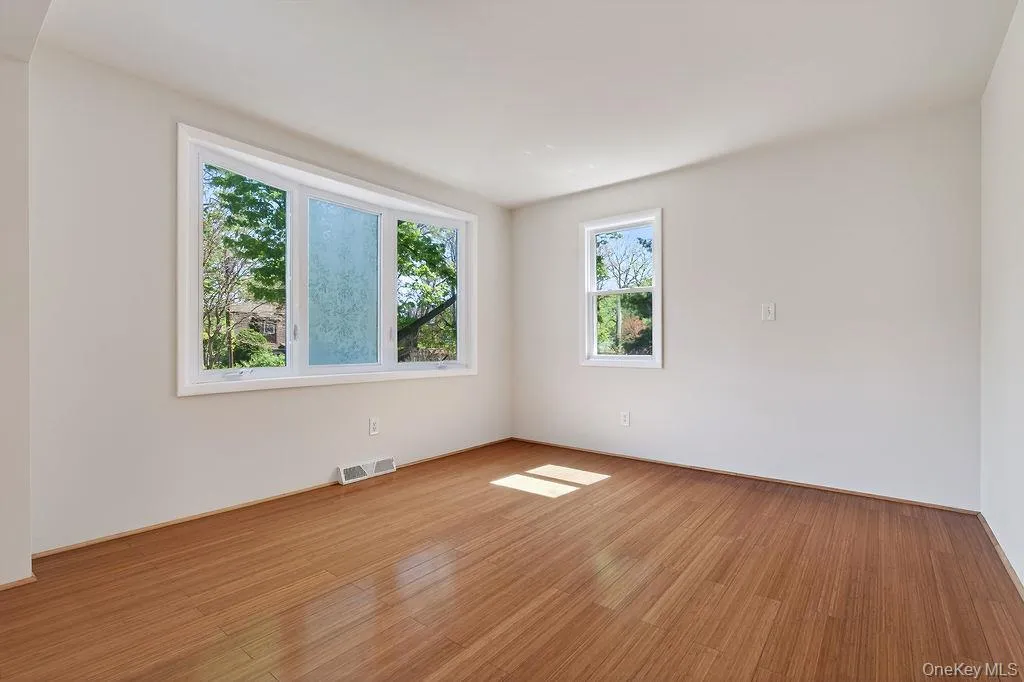 Spacious room featuring wood-finish flooring and a bay window Spacious room featuring wood-finish flooring and a bay window