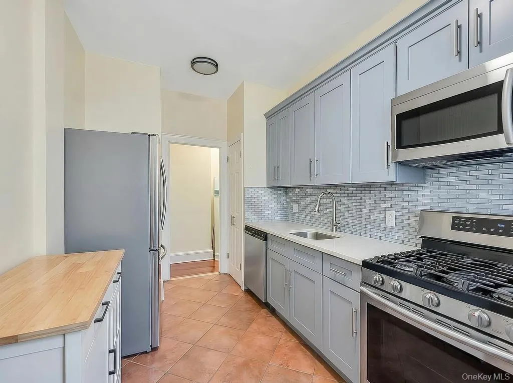 Updated kitchen with stainless steel appliances, light gray cabinetry, white countertops, and a white subway tile backsplash Updated kitchen with stainless steel appliances, light gray cabinetry, white countertops, and a white subway tile backsplash