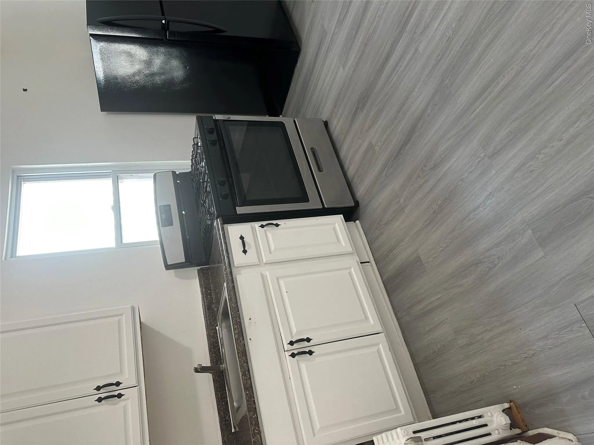 Kitchen featuring white cabinetry with dark hardware, a stainless steel range, and a dark refrigerator Kitchen featuring white cabinetry with dark hardware, a stainless steel range, and a dark refrigerator