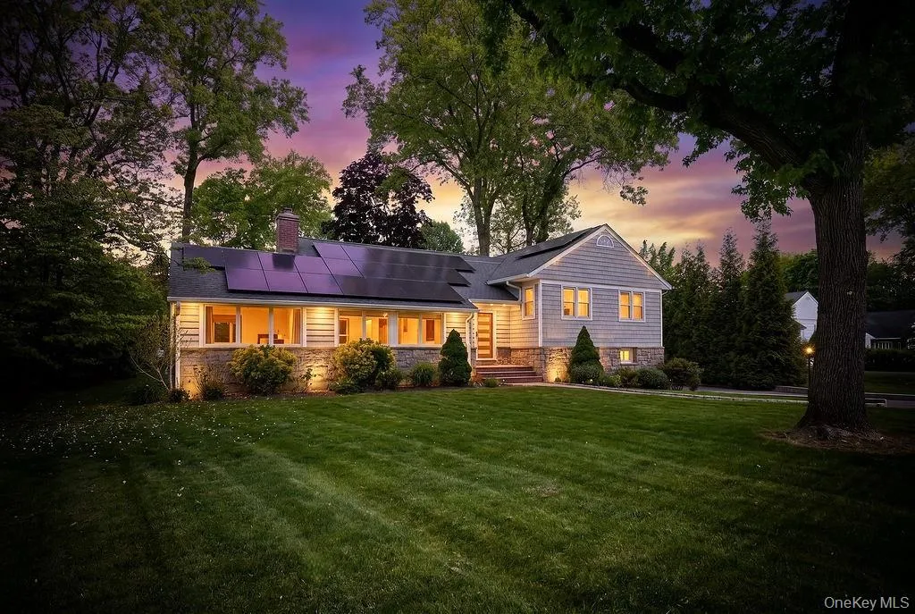 Lawn-front residence featuring stone accents, horizontal siding, and prominent roof-mounted solar panels Lawn-front residence featuring stone accents, horizontal siding, and prominent roof-mounted solar panels