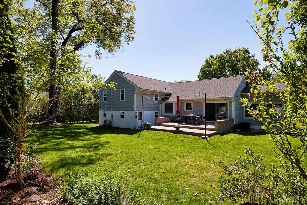 Expansive green lawn with mature trees and a multi-level stone patio Expansive green lawn with mature trees and a multi-level stone patio