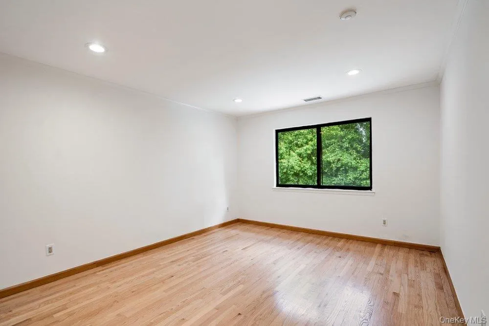 Hardwood flooring, recessed lighting, and a large window with a dark frame Hardwood flooring, recessed lighting, and a large window with a dark frame