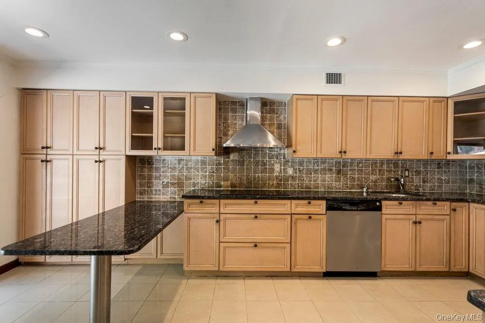 Kitchen featuring light wood cabinetry, dark speckled countertops, and a tiled backsplash Kitchen featuring light wood cabinetry, dark speckled countertops, and a tiled backsplash