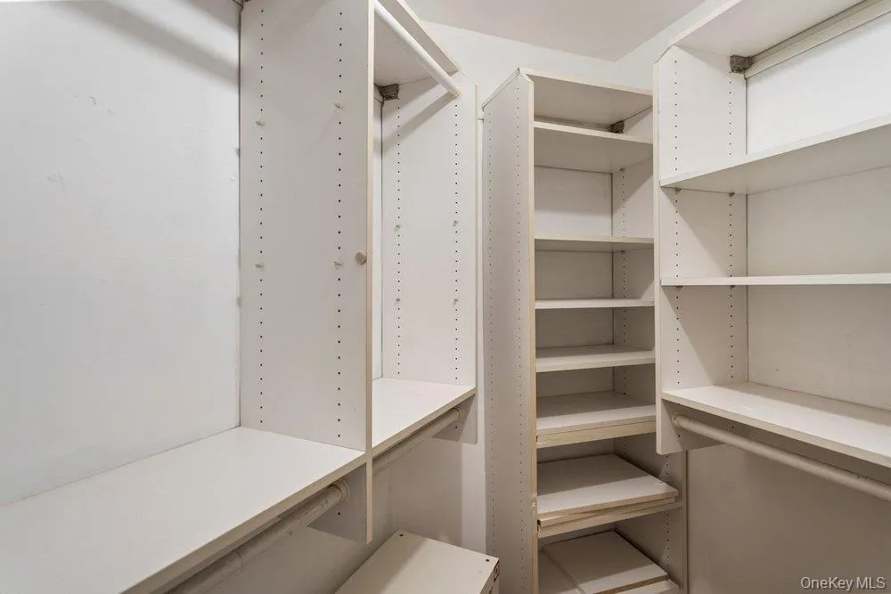 Walk-in closet featuring white shelving systems, multiple hanging rods, and adjustable shelves Walk-in closet featuring white shelving systems, multiple hanging rods, and adjustable shelves