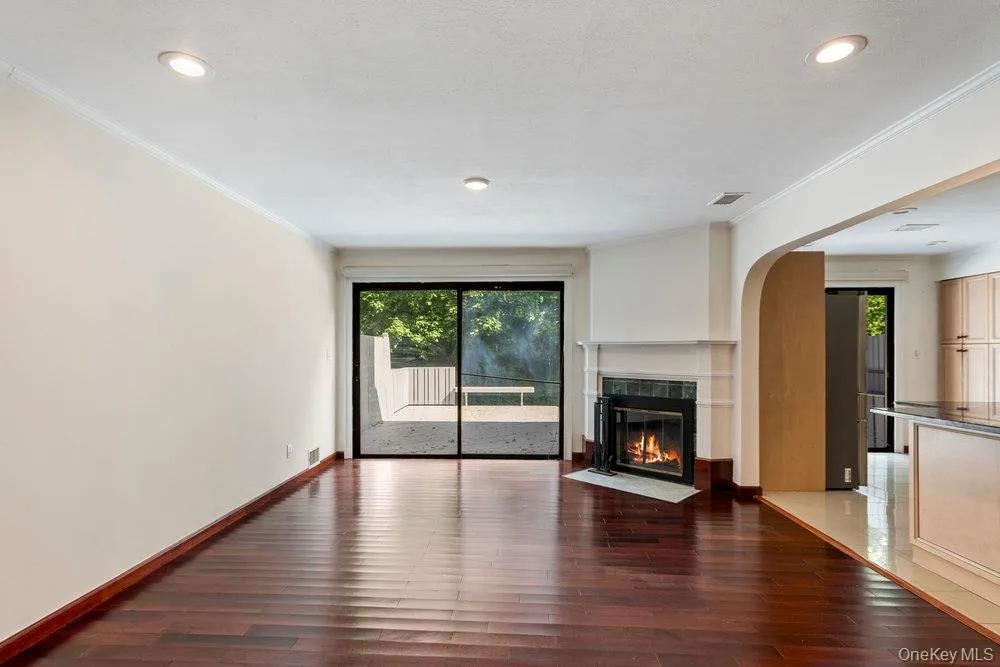 Spacious living area featuring rich wood-finish flooring, a contemporary fireplace with a classic mantel, and recessed lighting Spacious living area featuring rich wood-finish flooring, a contemporary fireplace with a classic mantel, and recessed lighting