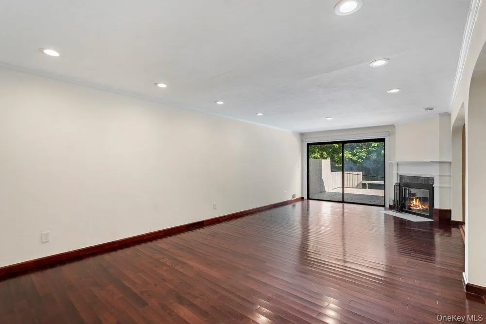 Spacious interior room featuring rich wood-finish flooring, recessed lighting, and white crown molding Spacious interior room featuring rich wood-finish flooring, recessed lighting, and white crown molding
